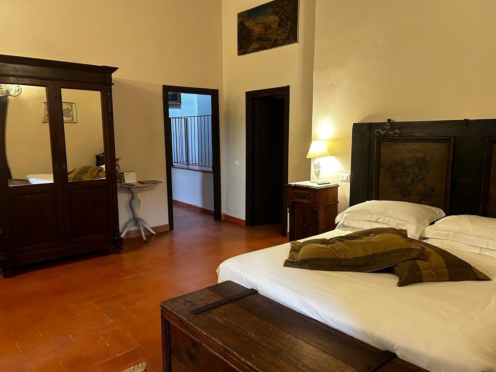A bedroom with a bed, bedside table, lamp, and a wooden wardrobe.