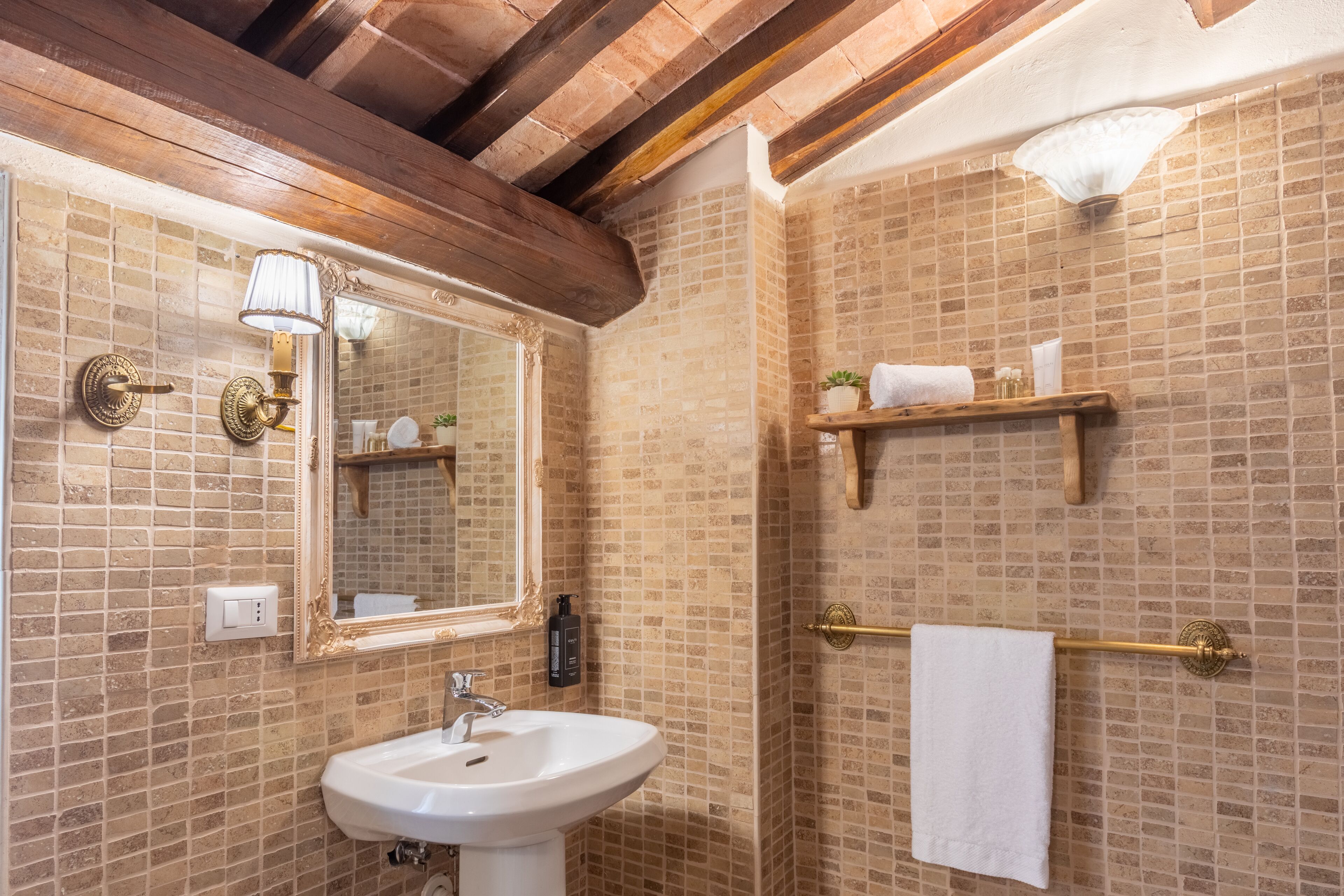 Un baño con lavamanos blanco, espejo, toallero y zona de ducha.