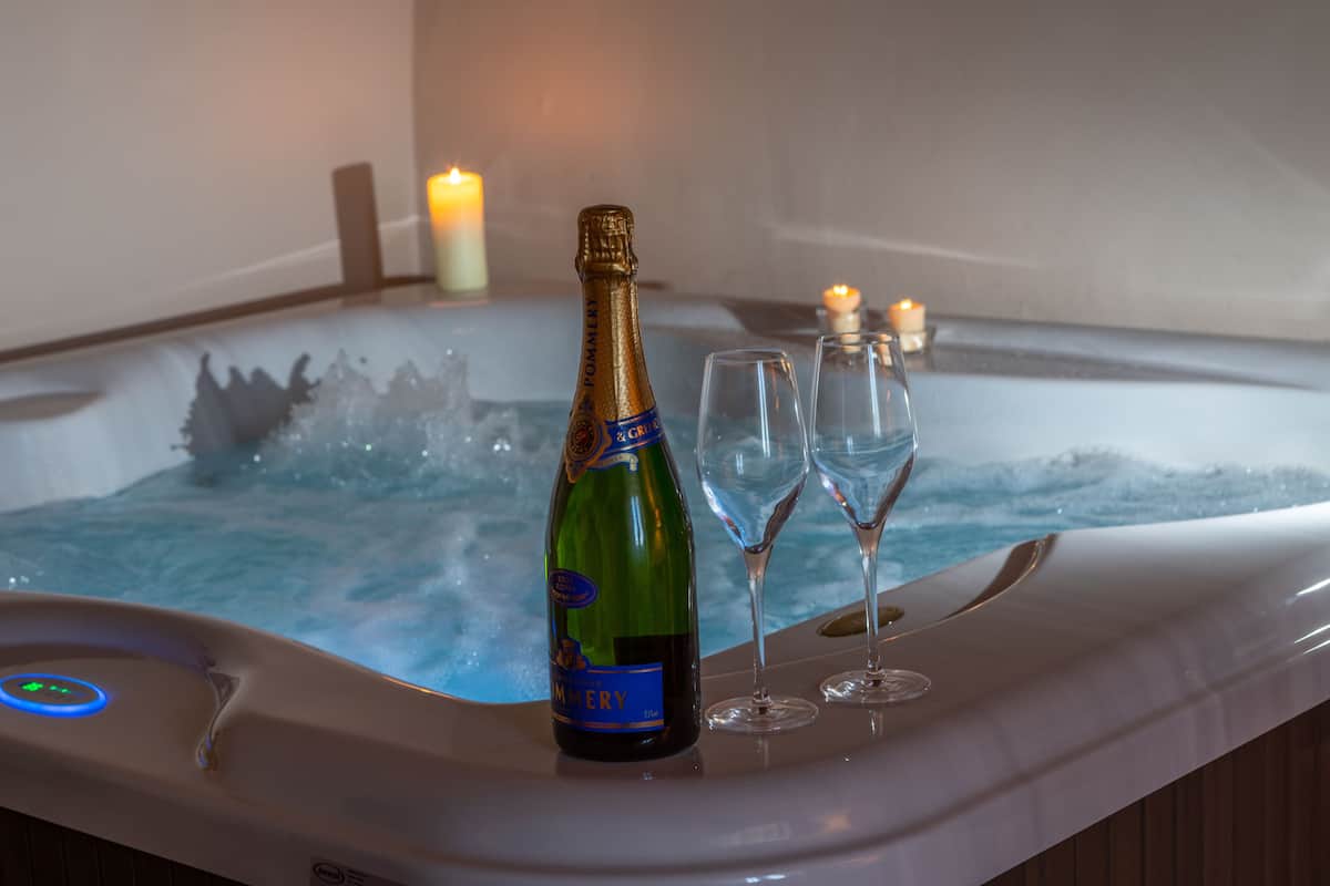 Un jacuzzi con una botella de champán y dos copas.