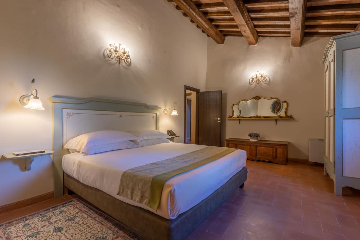 Un dormitorio con cama, mesita de noche, lámpara, espejo y armario.