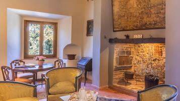 Ein gemütliches Wohnzimmer mit Kamin aus Stein, Holzbalken und einem großen Gemälde an der Wand.