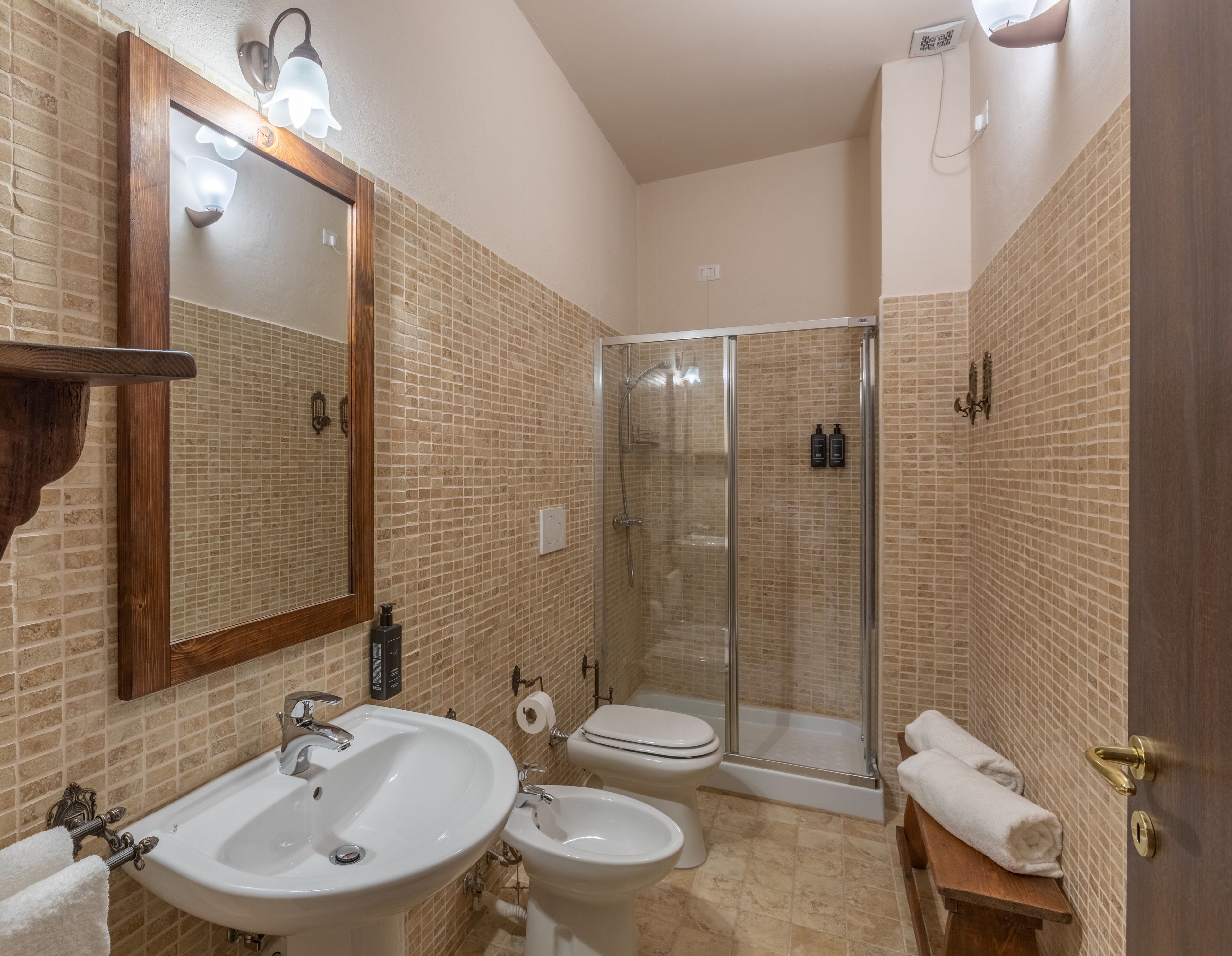 Un baño con un espejo grande, dos lavamanos, un inodoro, una ducha y un perchero para toallas.