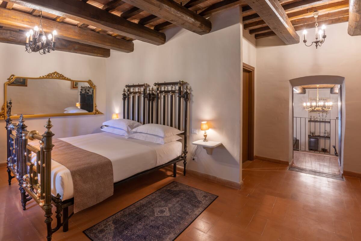 Un dormitorio con una cama grande, techo de madera, un espejo y un radiador.