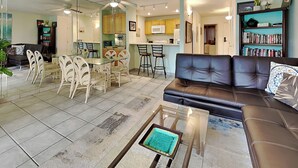 Un salon moderne avec une table basse en verre, un canapé en cuir et un coin repas avec des chaises en osier.