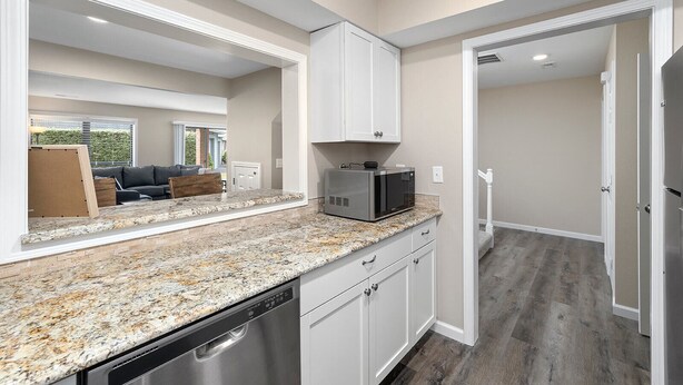 A modern kitchen with granite countertops, white cabinetry, and stainless steel appliances. - WALK IN, Pointe Royale, Arcade, Indoor Pool (Branson)