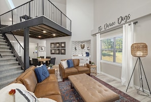 Relax in this stylish living room with a sofa set, ottoman, and floor lamp, surrounded by framed artwork and a view of lush greenery.