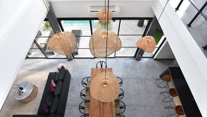 A modern interior with a wooden dining table, black sofa, and wicker pendant lights. - Villa Soho (Canggu)