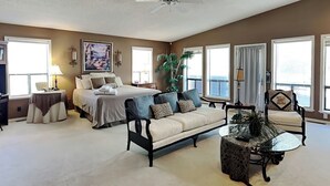 Un'ampia camera da letto con un letto grande, un'area salotto con divano e poltrone, e una ventola a soffitto.
