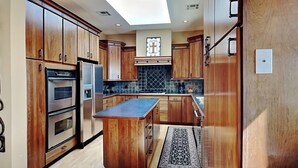Una cucina moderna con mobili in legno, elettrodomestici in acciaio inossidabile e un lucernario.