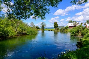 A river flowing through a lush landscape with trees and a house on the right bank.