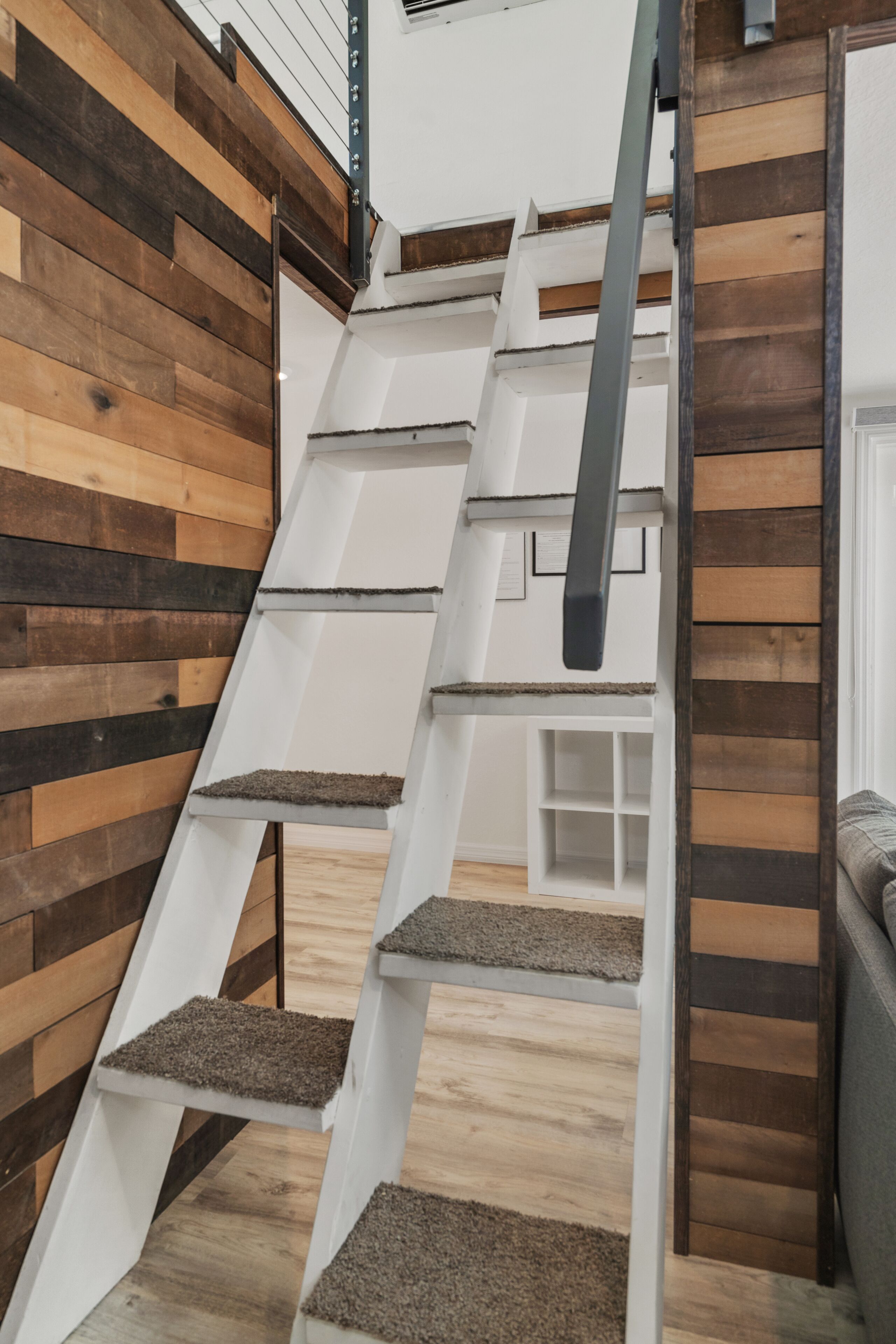 A staircase with a wooden wall and a white railing.