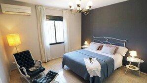 Ein Hotelzimmer mit Bett, Stuhl, Lampe und Fenster.