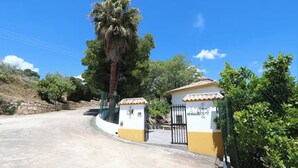Ein verschlossenes Tor mit einem kleinen Gebäude, auf dem "EL CARMEN" steht, und einer Palme.