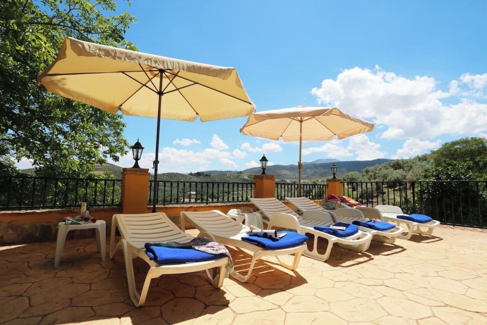 A terrace with lounge chairs and umbrellas, overlooking a scenic landscape.