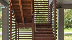 Una escalera de madera bajo una zona techada con suelo de grava.