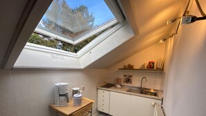 Une cuisine compacte dotée d’un puits de lumière, d’une machine à café, d’une bouilloire et d’un petit plan de travail.