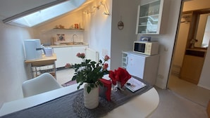 Une cuisine compacte dotée d’une lucarne, un coin repas avec une table et des chaises, et un petit réfrigérateur.