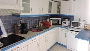 Una cocina con armarios blancos, una estufa negra, un microondas, un tostador y un lavabo.