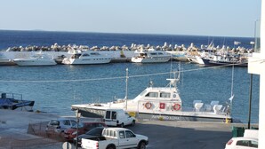 Una marina con varios barcos amarrados, una camioneta blanca y algunos coches estacionados en la orilla.