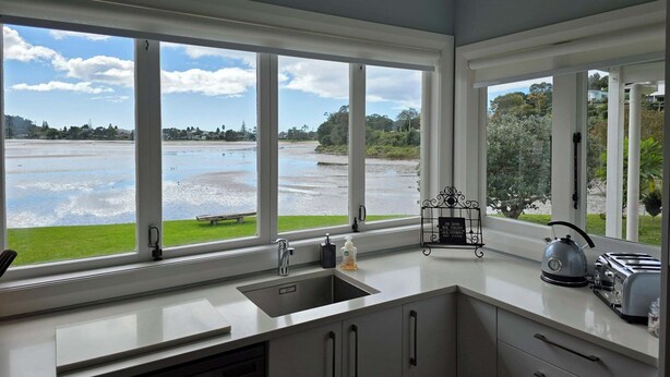 A kitchen with a large window overlooking a river, a kettle, and a toaster on the counter.