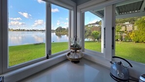 A room with large windows, a kettle, and a tray with glassware.