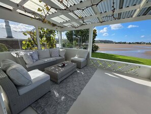 Un espace extérieur aménagé, abrité et doté d’un canapé, de deux fauteuils et d’une table basse.