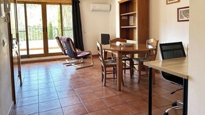 Un coin repas avec une table et des chaises en bois, une bibliothèque et une vue dégagée grâce à de grandes fenêtres.