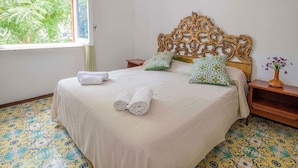 A bed with a decorative headboard, two pillows, a rolled towel, and a nightstand with a vase of flowers. - Apartment Bianca with shared pool (Sorrento)