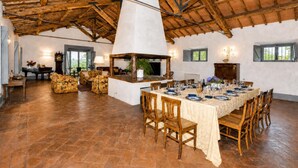 A spacious dining area with a high ceiling, wooden beams, and a large table set for a meal. - Casale Teresa (Tarquinia)