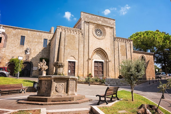 A historic building with a large clock tower, a fountain, and benches in a public square.