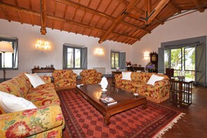 A spacious living room with floral sofas, a wooden coffee table, and a red patterned rug.