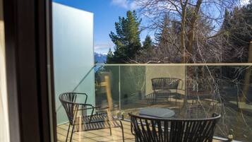 Un balcon doté d’une barrière en verre, de deux chaises et d’une table.