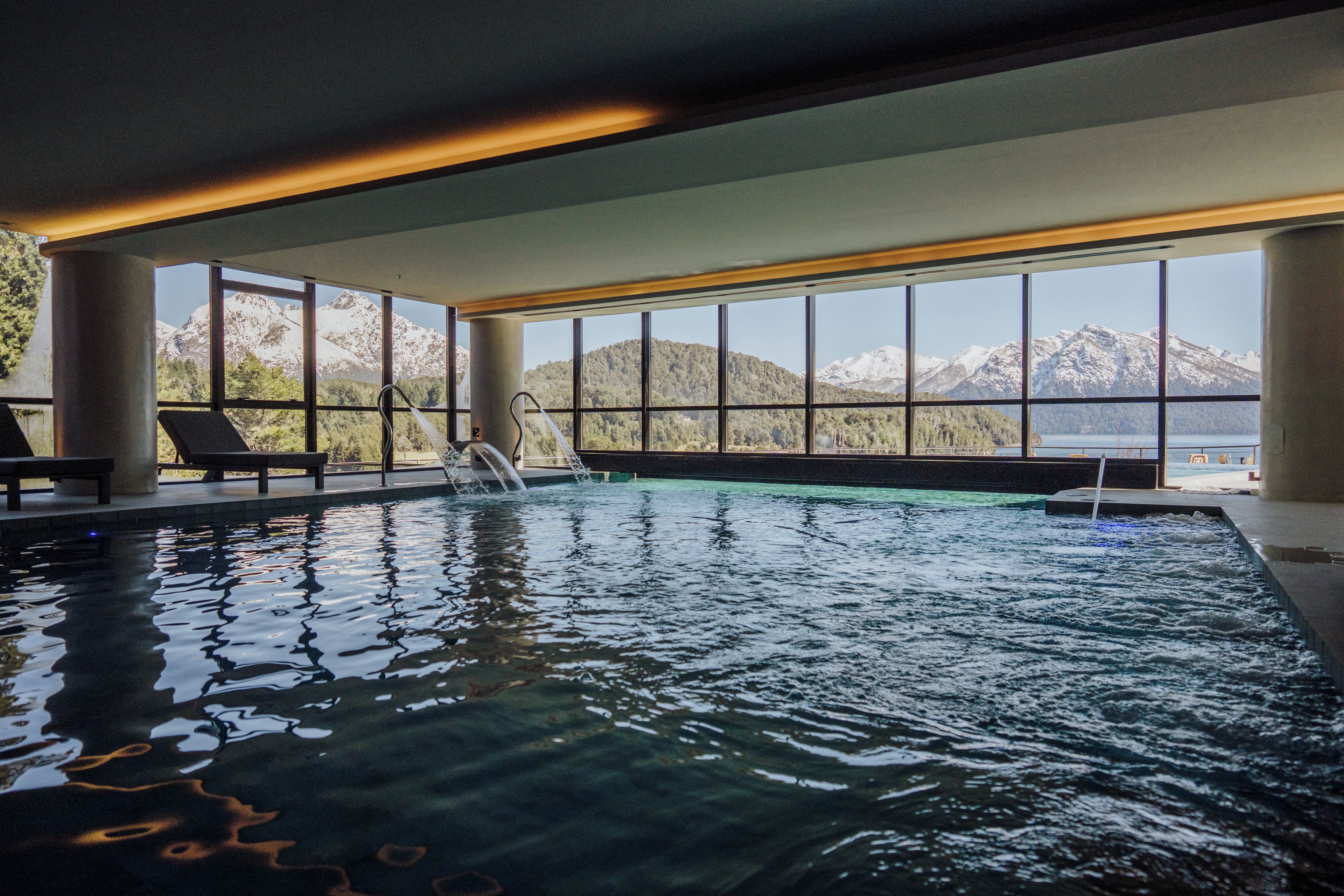 Una piscina interior con vistas despejadas a montañas a través de amplias ventanas.