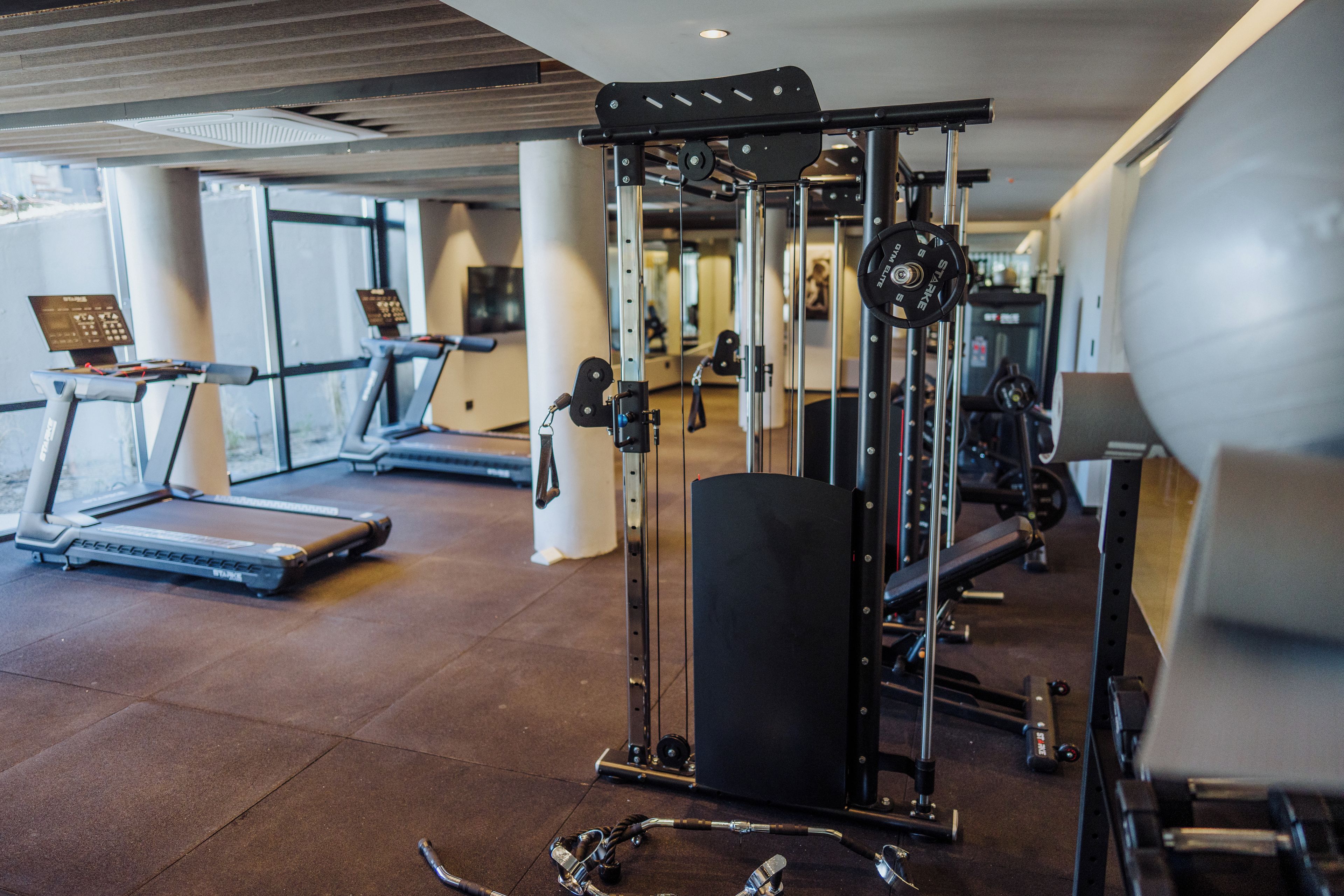 A gym with treadmills, weight machines, and a large exercise ball.