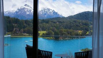 Une pièce avec vue sur un lac et des montagnes. Elle contient deux chaises et une petite table.