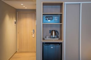 A compact kitchenette with a coffee maker, a small refrigerator, and a built-in oven.