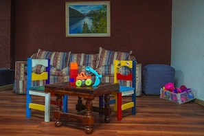 Una habitación acogedora con una mesa de madera, sillas coloridas, un sofá y un cuadro en la pared.