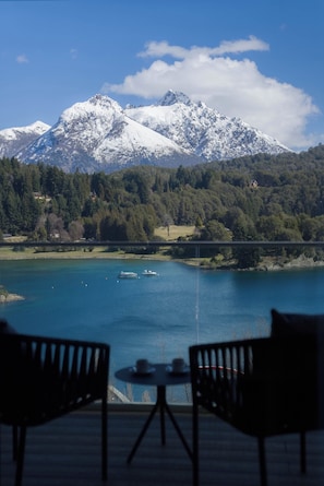 A view of a lake with boats, a mountain range, and a forested area.