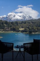 A view of a lake with boats, a mountain range, and a forested area.