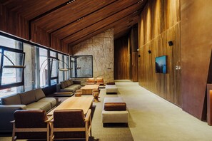 Un área de descanso moderna con un banco de madera largo, asientos acolchados y una pared de piedra.