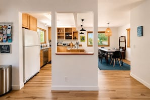 A modern kitchen with wooden cabinets, a central island, and a dining area with a table and chairs.