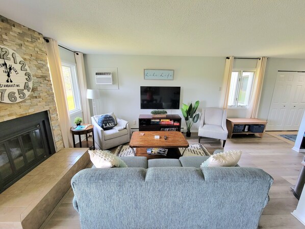 A living room with a fireplace, a television, a striped sofa, and a striped armchair.