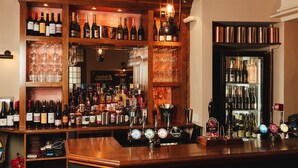 A bar with multiple shelves of bottles and glasses, a variety of taps, and a mirror reflecting the interior. - The Falcon Painswick (Stroud)