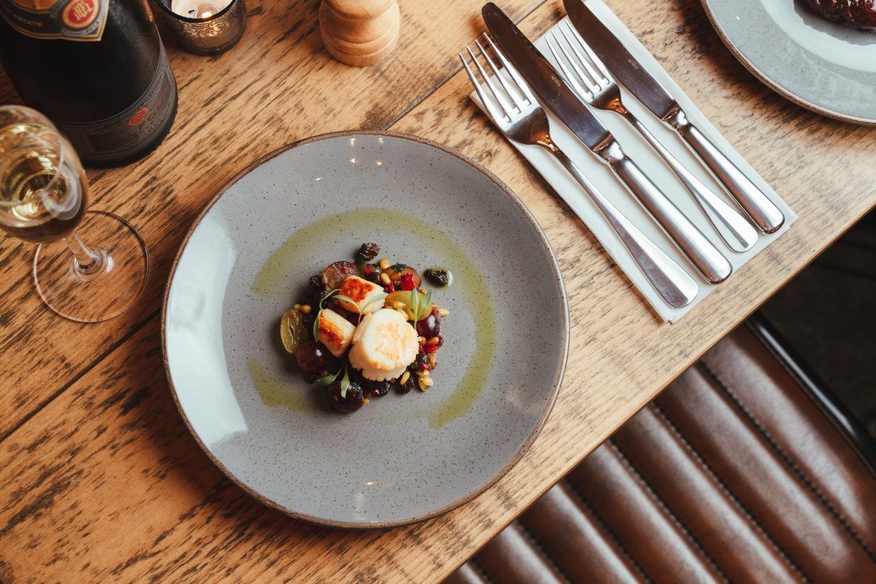 A dining table with a plate of food, a wine glass, and cutlery.