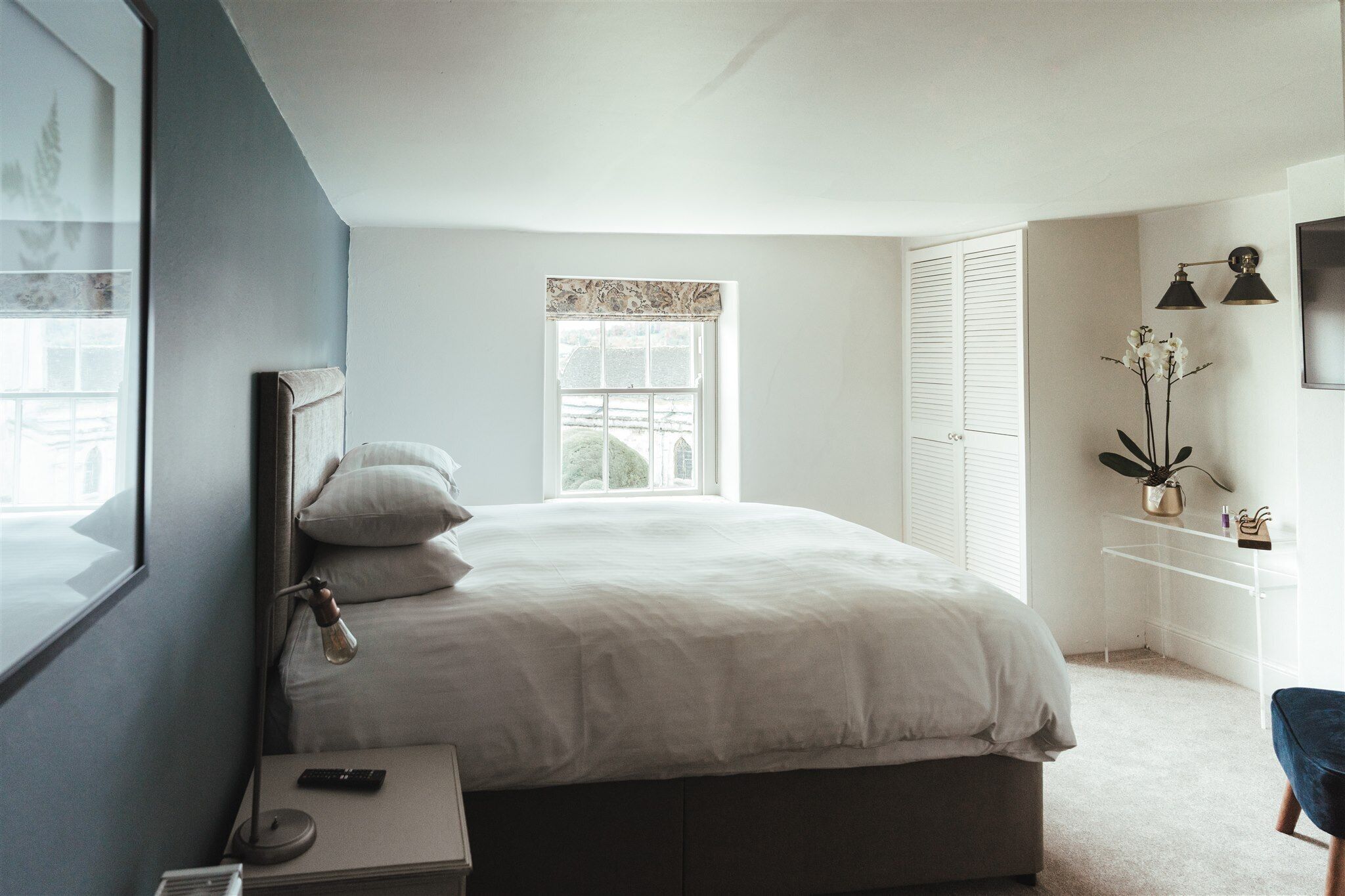 Un dormitorio con cama, lámpara de noche y mesita de noche.