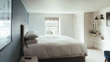 Un dormitorio con cama, lámpara de noche y mesita de noche.