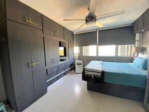 Un dormitorio con cama, ventilador de techo y armarios oscuros.
