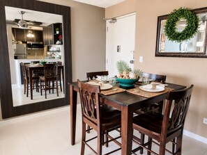 A dining area with a dark wooden table, chairs, and a kitchen visible through a mirror. - Beachfront Gem Washer/D Walk Everywhere (Carolina)