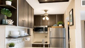 Una cocina moderna con electrodomésticos de acero inoxidable, armarios de madera y una encimera blanca.
