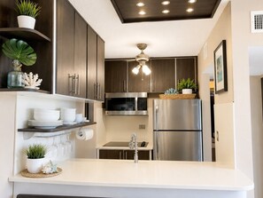 Una cocina moderna con electrodomésticos de acero inoxidable, armarios de madera y una encimera blanca.